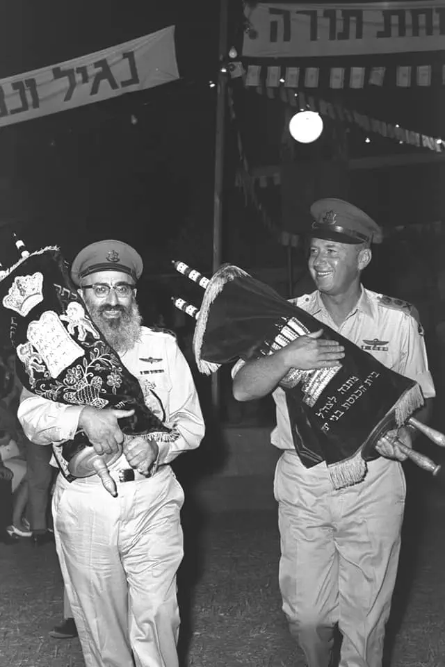 הרמטכ"ל, רב אלוף יצחק רבין והרב הראשי של צה"ל, הרב שלמה גורן, מחזיקים ספרי תורה בעת חגיגות שמחת תורה בבסיס צבאי, 1966
