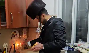 Father still smiling as he lights Shabbat candles alone