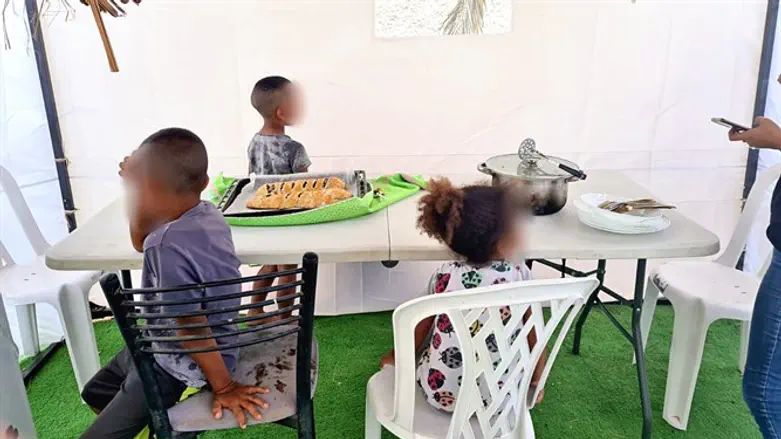 Дети выжившего из Хеврона сидят в сукке.