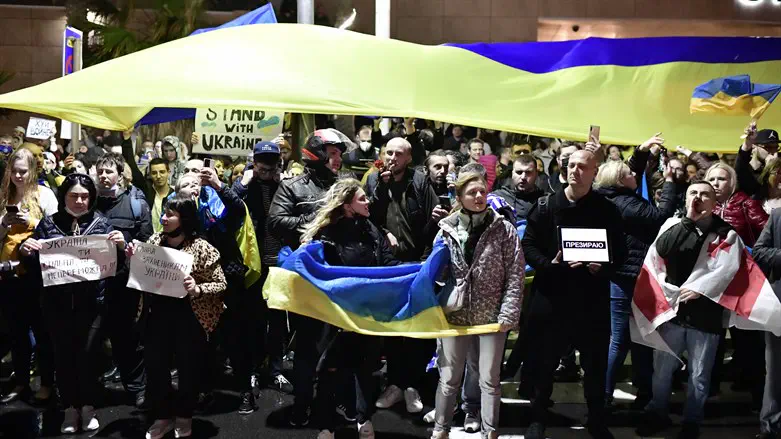 Demonstrators carry placards and flags during a protest outside the Russian Embassy