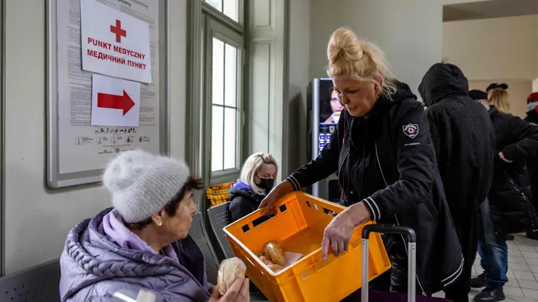 Volunteer offers sandwiches to Ukrainian woman in the main railway station of Przemysl