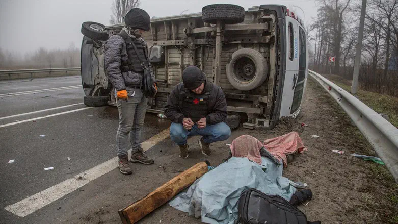A volunteer inspects a body of killed person on a street in the town of Bucha