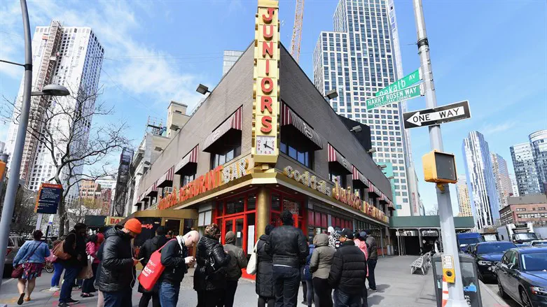 People stand in line outside Junior's restaurant in Brooklyn to pick up food to 