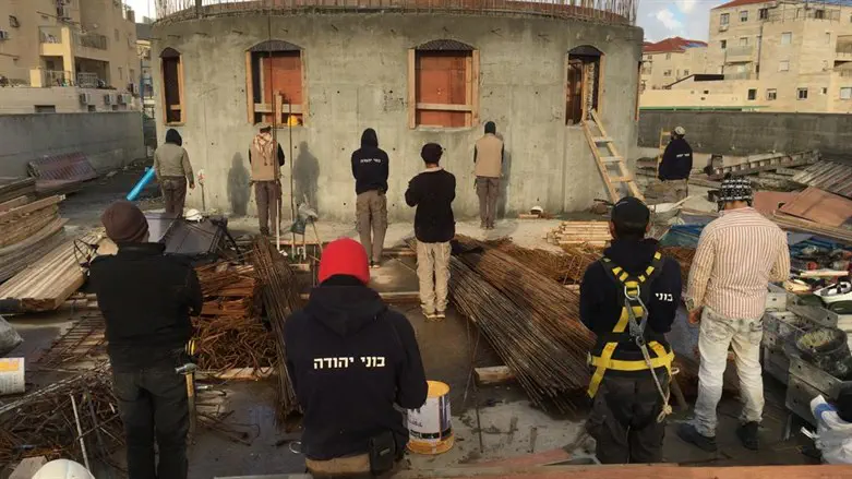 Construction workers davening Minchah on a roof 