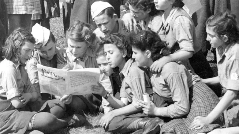 Children from the Jaeger Kaserne DP camp in Germany read a Yiddish newspaper