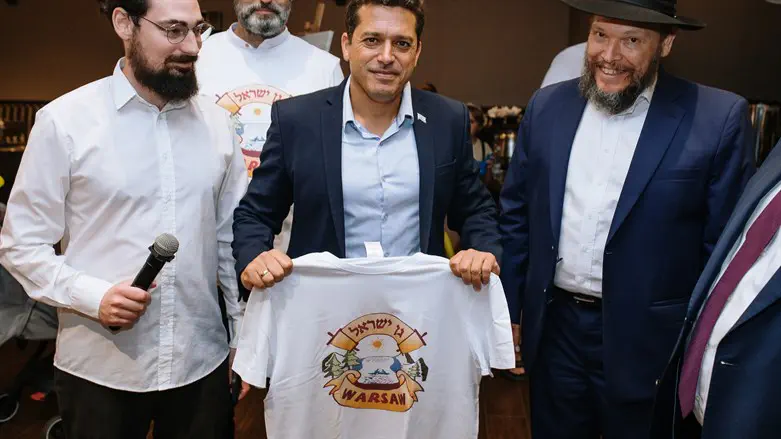 Amichai Chikli holds a Gan Israel summer camp shirt