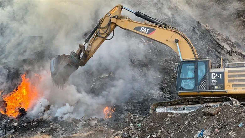 A bulldozer works to extinguish flames at the Arab illegal dumping site