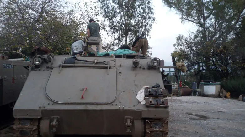 Volunteers attach armor to an APC