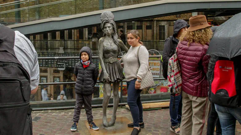Tourists pose beside statue of Amy Winehouse