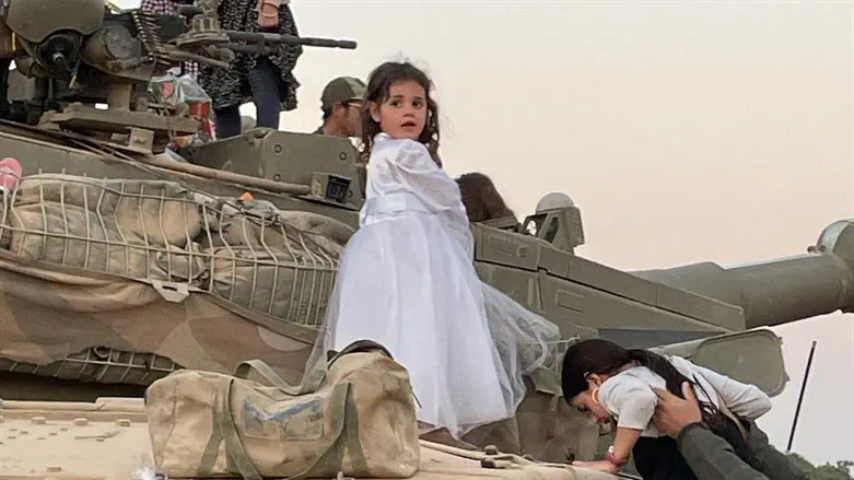 A girl in costume climbs an IDF tank