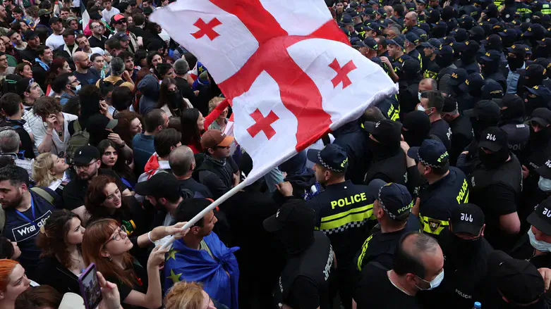 A woman waves Georgia's flag as she protests outside the parliament building in Tbilisi