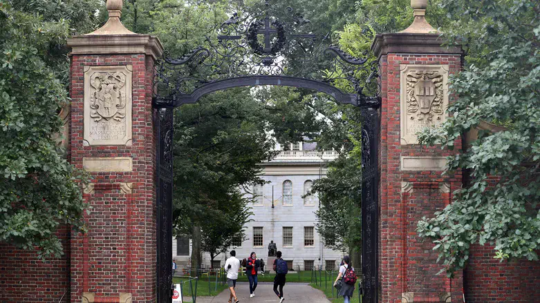 Students walk by the Harvard Yard gate in Cambridge, Massachusetts