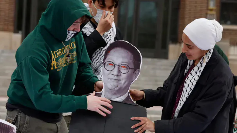 Pro-Palestinian demonstrators adjust a photo of University of Michigan President Santa Ono