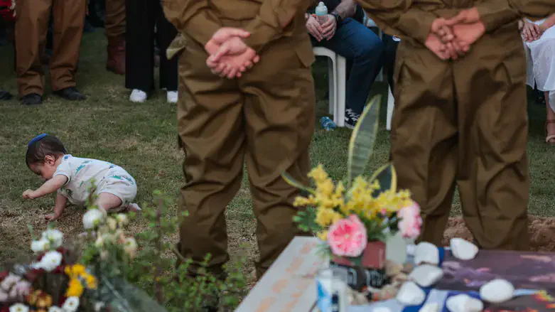 Nine-month-old Lior crawls beside his father's fresh grave