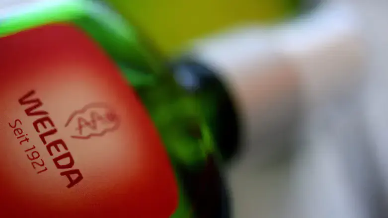 Weleda's logo on a glass bottle. Weleda produces herbal medicines and cosmetics.