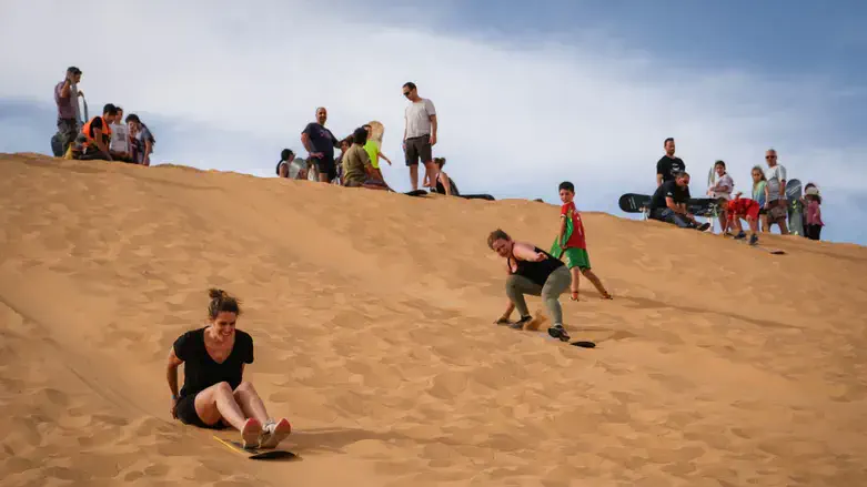 Israelis surf on a sand dune in the Negev