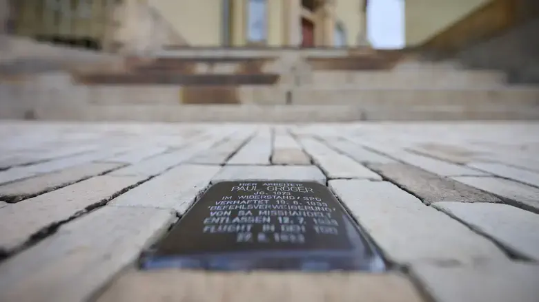 A Stolperstein embedded in the sidewalk in front of City Hall.