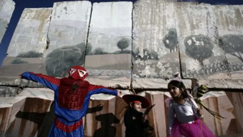 Children in Purim costumes next to Gilo wall