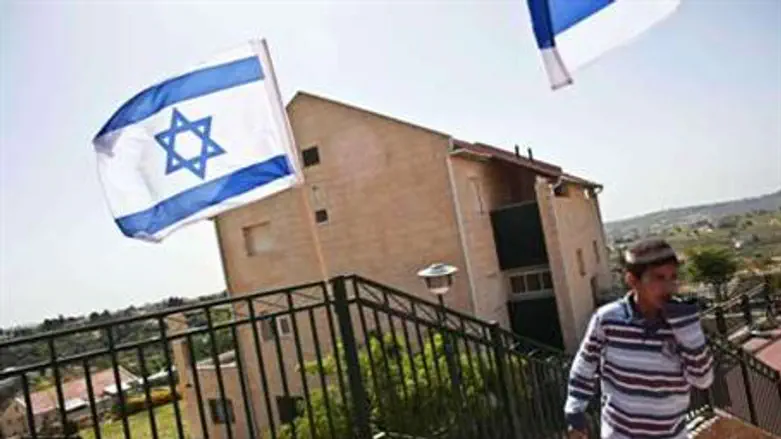 A boy walks near Israeli flags in Ulpana
