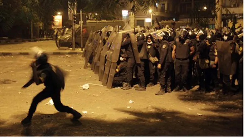 Riot policemen take cover from stones thrown