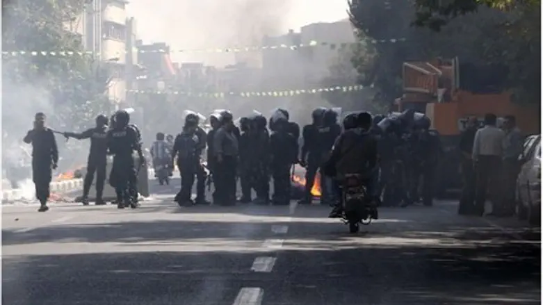Iranian riot police stand next to a waste bin
