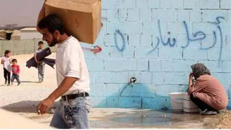 A Syrian refugee collects water at a refugee