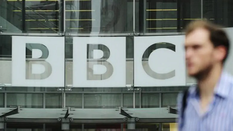 A pedestrian walks past a BBC logo