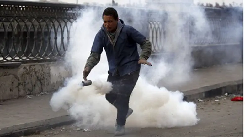 A protester flees from tear gas fired by riot