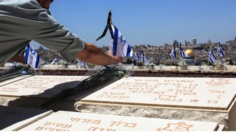 An Israeli soldier placing a flag on the grav