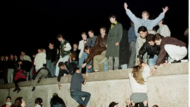 East Germans climb the Berlin Wall after fall
