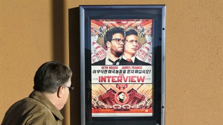 A man walks by the poster for the film "The Interview"