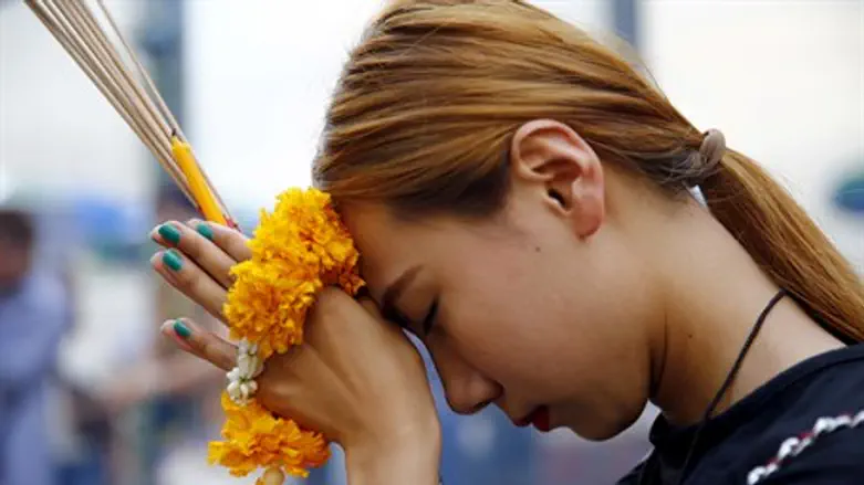Woman prays at the Erawan Shrine in Bangkok following attack