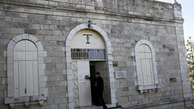 A Greek Orthodox monk cleans graffiti on Jerusalem's Dormition Abbey