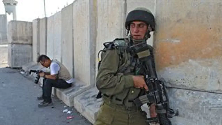 חייל בודק ערבים במחסום