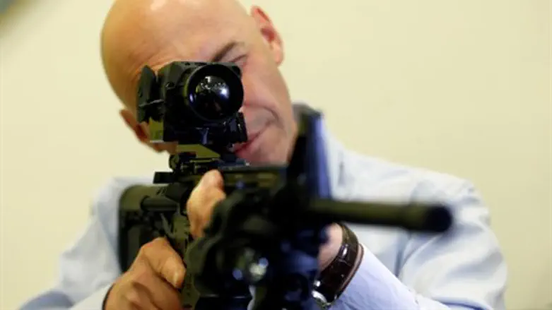 Man looks through infrared scope on a weapon during a preview presentation at Elbit System