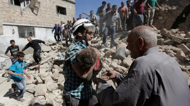A child's body is carried away fromthe site of a regime bombing in Idlib, Syria