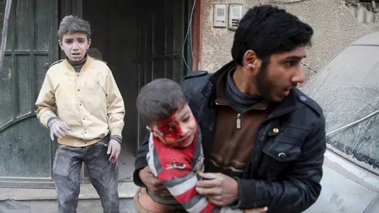 Syrian man carries boy injured by regime shelling