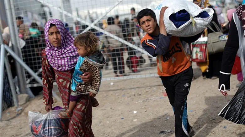 A displaced Iraqi girl carries a child as they arrive at Hammam al-Alil camp, south of Mos