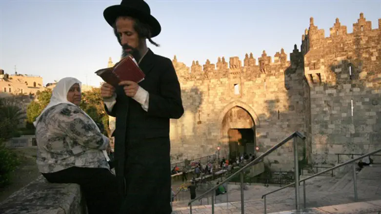 Haredi man passes Arab woman near Damascus Gate in Jerusalem