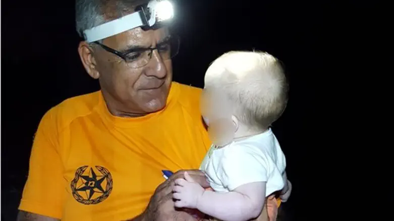 A rescuer carries a baby out of the stream