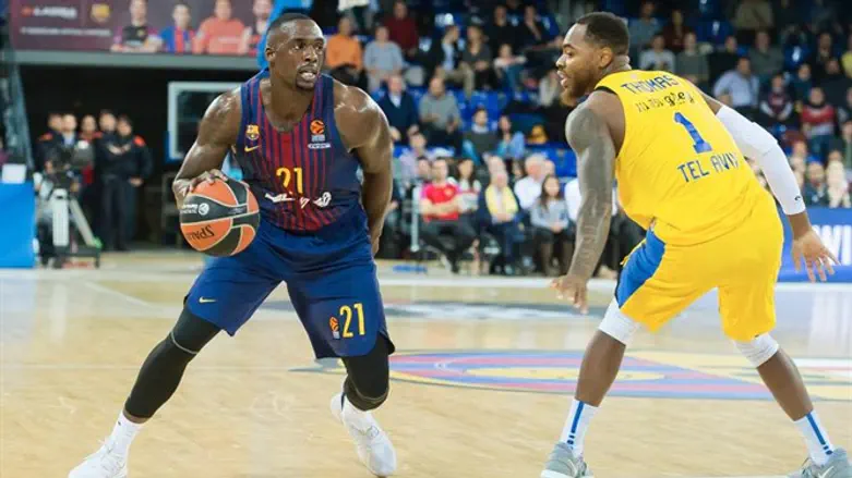 דשון תומאס מנסה לעצור שחקן של ברצלונה