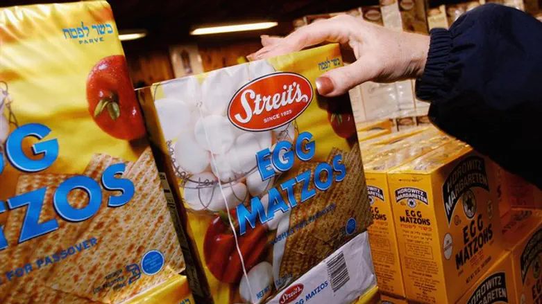 An illustrative photo of a shopper at a grocery store picking up a box of matzah