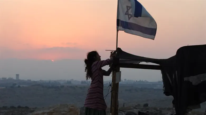 Jewish girl raises Israeli flag at the Israeli village of Avnei Hefetz, Samaria