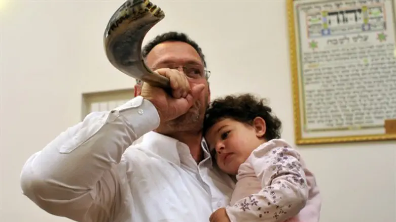 Father blows the shofar with his child