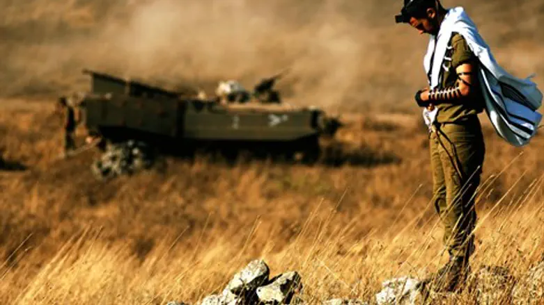 Religious IDF soldier prays near his APC
