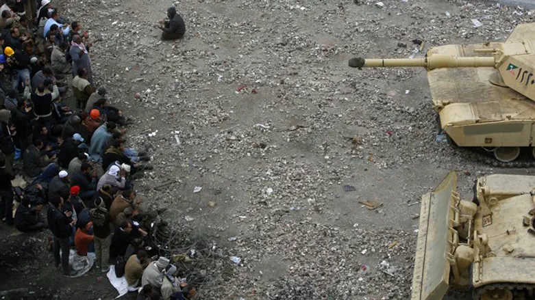 Arab Spring: anti-government protester prays as comrades face tanks, 2011