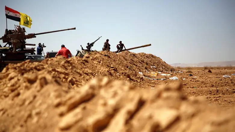 Hezbollah and Syrian flags flutter on a military vehicle in Western Qalamoun, Sy
