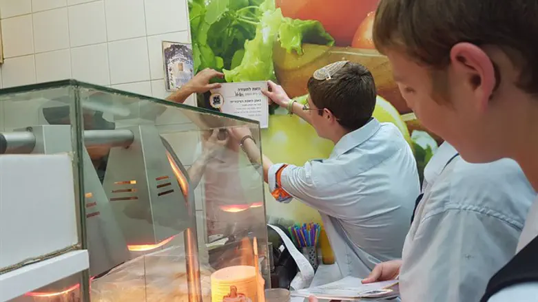 חברי בני עקיבא תולים את תעודת "נאמן השבת הציבורית" בעסק בבאר שבע