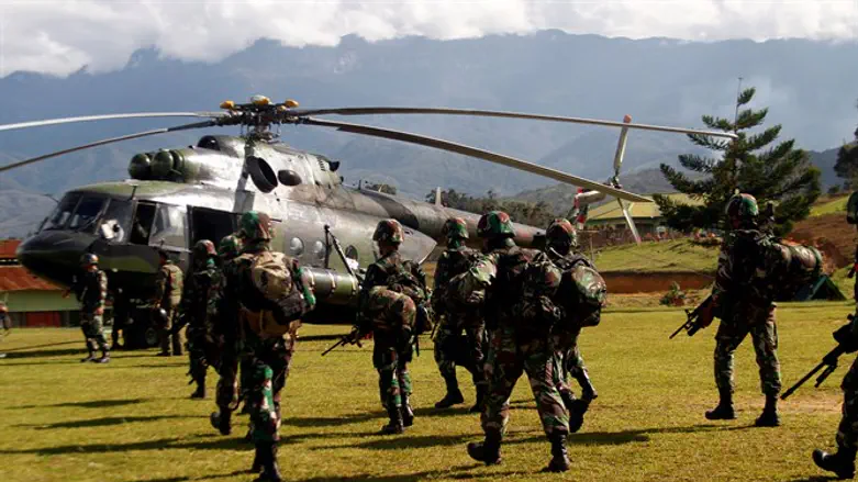 Indonesian soldiers carry rifles as they walk towards helicopter to fly to Nduga