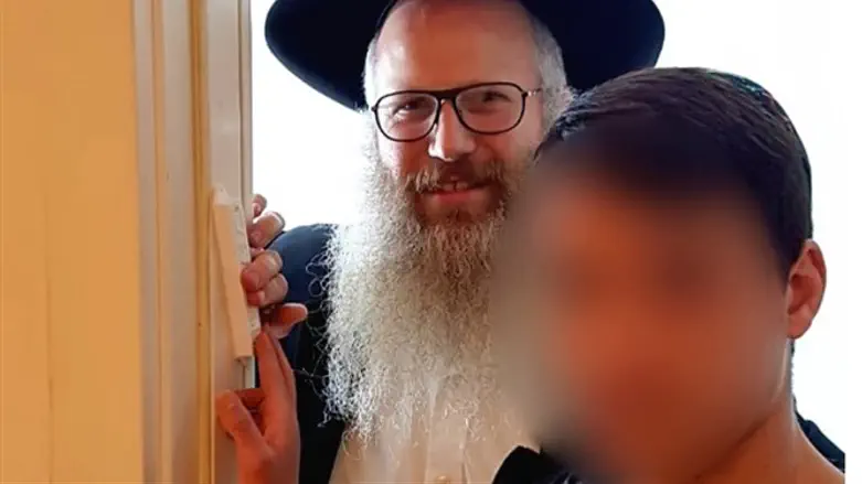L. and Rabbi Robinson affix a mezuzah to the door of his new home.